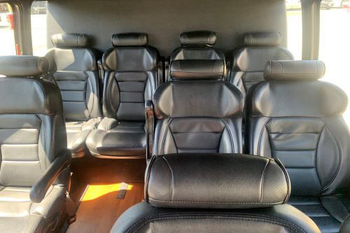 Spacious shuttle interior with rows of black leather seating, offering comfort for groups traveling on Californiawinetours.