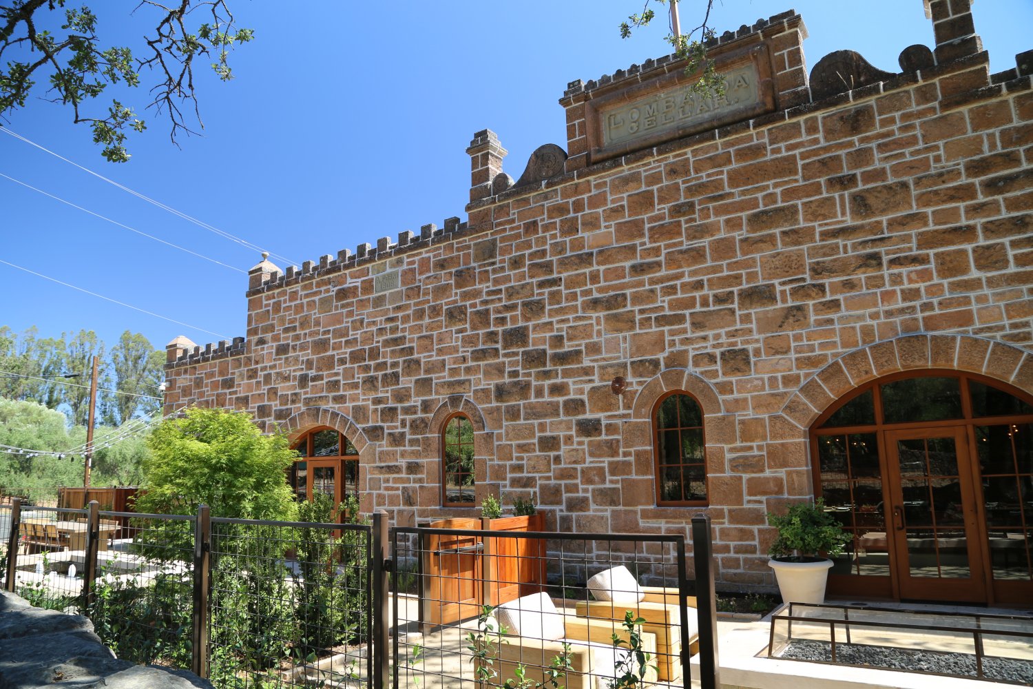 A large building with a fence, identified as Freemark Abbey, set against a clear blue sky.