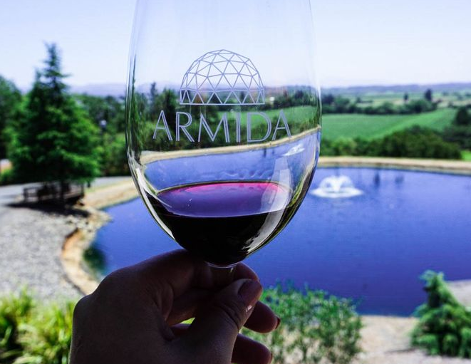 holding wine glass in front of pond at arminda
