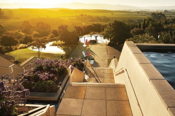 A serene sunset casts warm hues over a tranquil swimming pool at Artesa, creating a peaceful evening atmosphere.