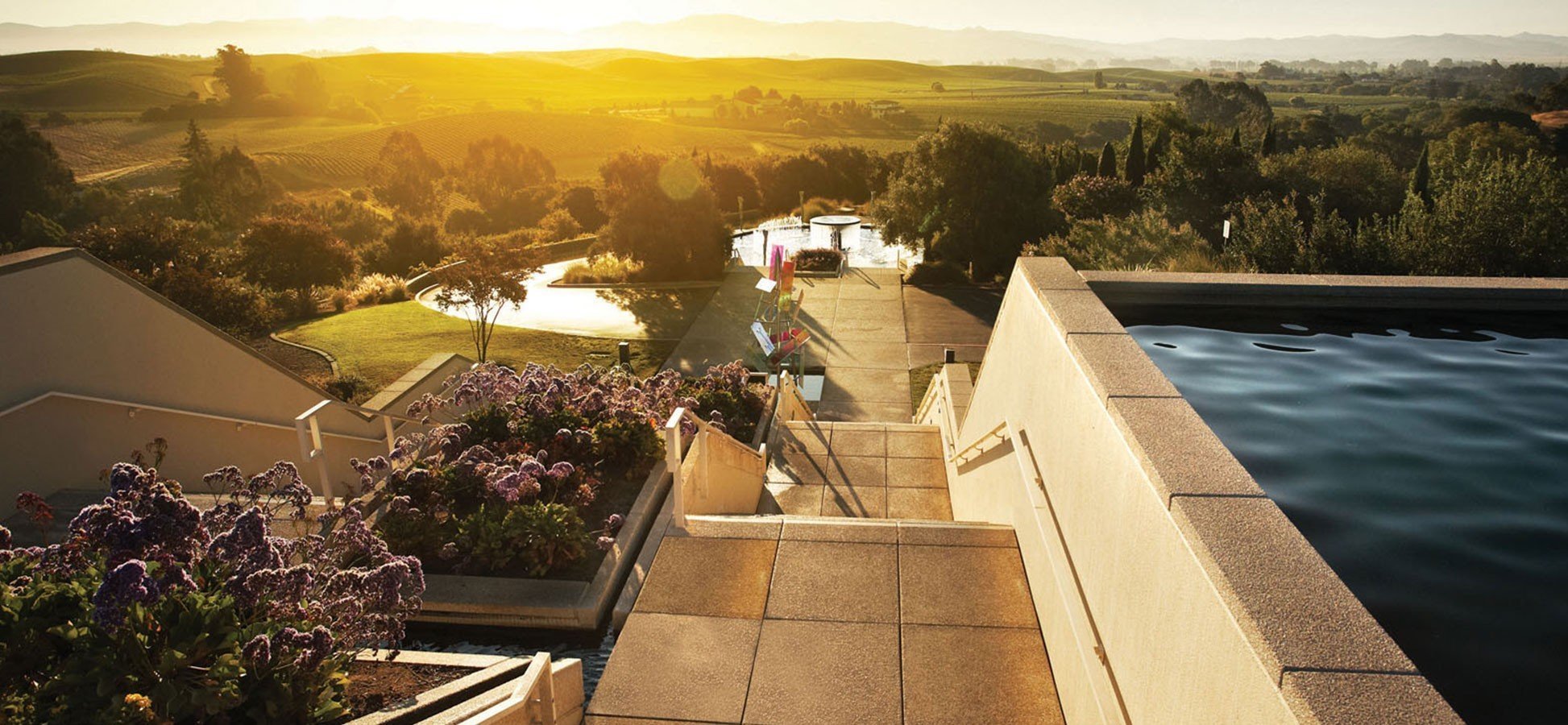 artesa A serene sunset casts warm hues over a tranquil swimming pool at Artesa, creating a peaceful evening atmosphere.
