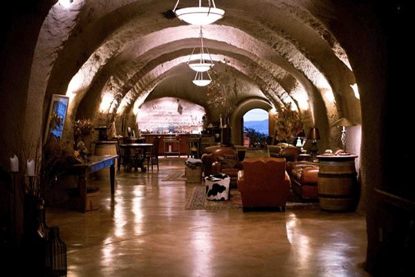 Inside Bwise Winery, a long tunnel showcases a bar and chairs, blending rustic charm with a cozy ambiance.