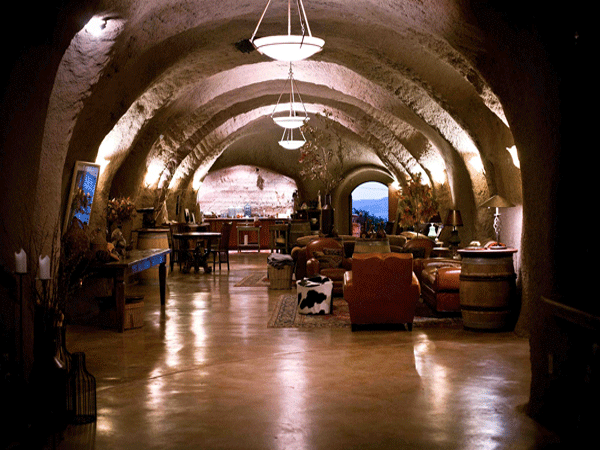 Inside Bwise Winery, a long tunnel showcases a bar and chairs, blending rustic charm with a cozy ambiance.