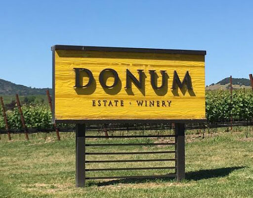Donum Estate Winery sign inviting visitors to the tasting room, showcasing the winery's branding and welcoming atmosphere.