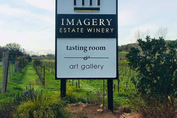 Imagery Estate Winery sign located in a vibrant field, highlighting its tasting room and art gallery.