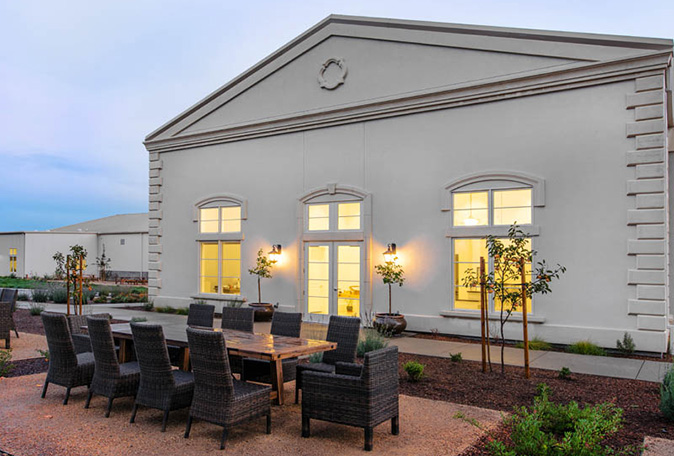A patio featuring a table and chairs in front of a white building, creating a welcoming outdoor space.