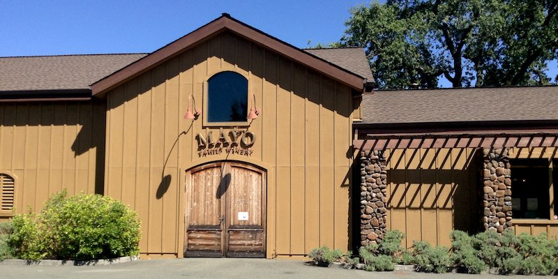 Front view of Mayo Family Winery building with a sign reading "Ola" prominently displayed.