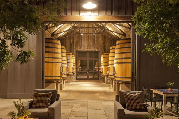 A wine cellar in Ramsgate featuring chairs and tables arranged in front of wooden barrels.