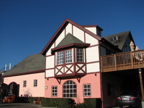 A picturesque pink and white house with a balcony, exuding charm and warmth in a serene neighborhood setting.
