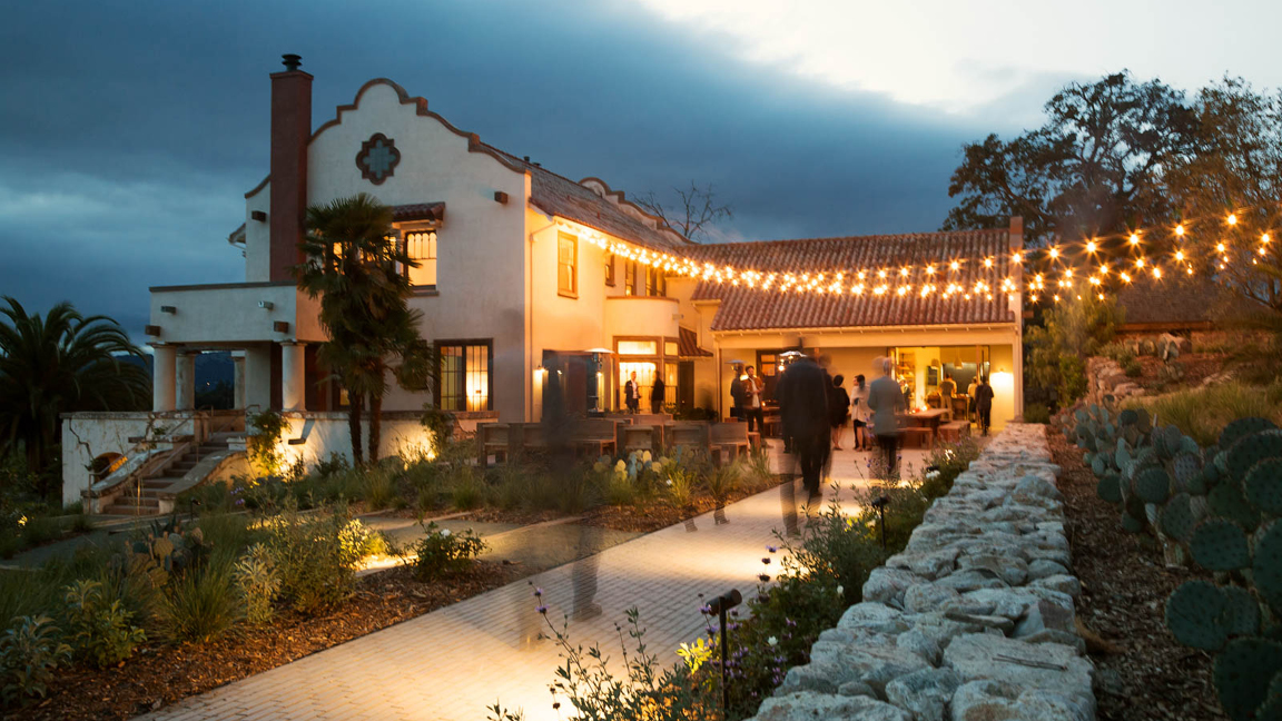 A cozy house adorned with string lights illuminating the walkway, creating a warm and inviting atmosphere.