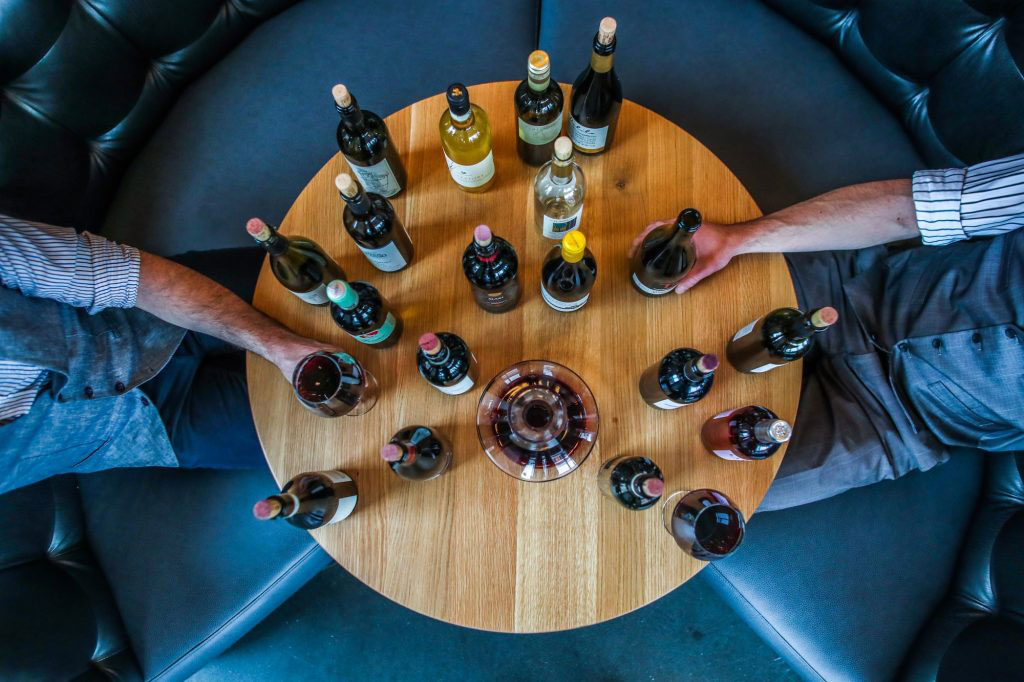 a table with wine bottles and people sitting near