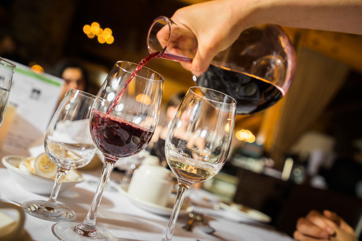 person pouring wine in a glass