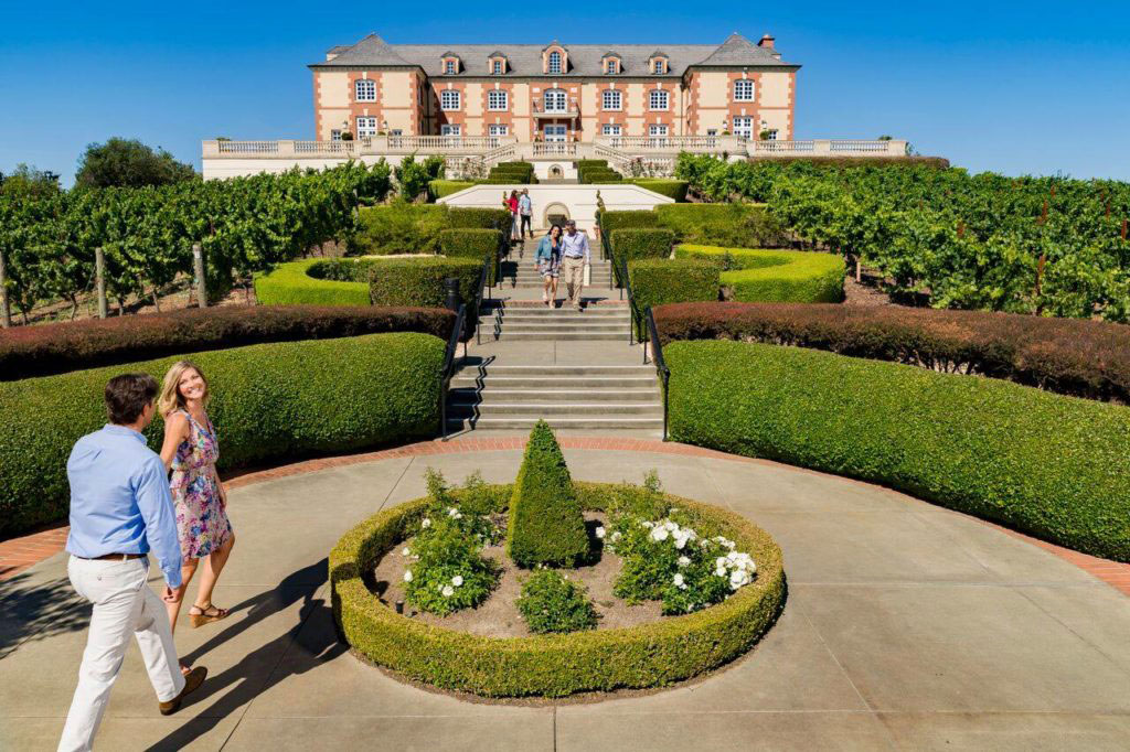 people walking towards a beautiful winery surrounded by nice gardens