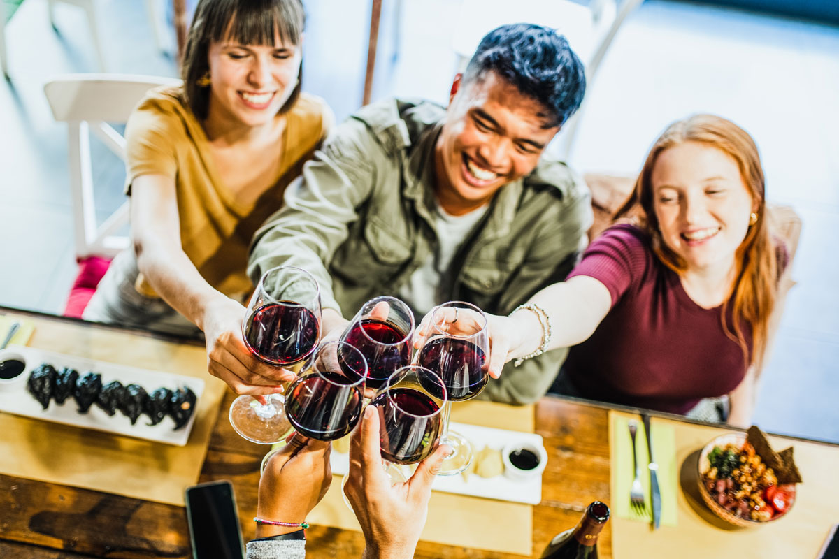 freinds cheers-ing their wine glasses at a table