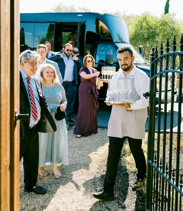 service person holding tray of champagne for guests as they exit shuttle