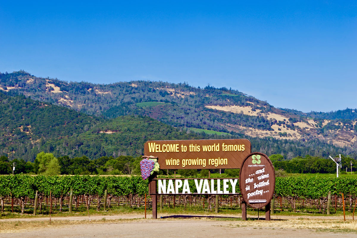napa valley welcome sign in front of vineyard and hill