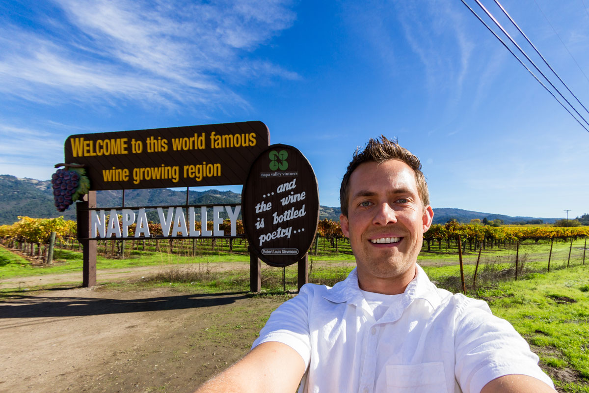 tourist wine tasting and taking a photo at the Napa Valley enterance sign